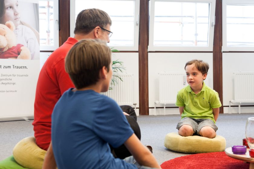 Ein Johanniter sitzt zusammen mit Kindern in einem Sitzkreis.