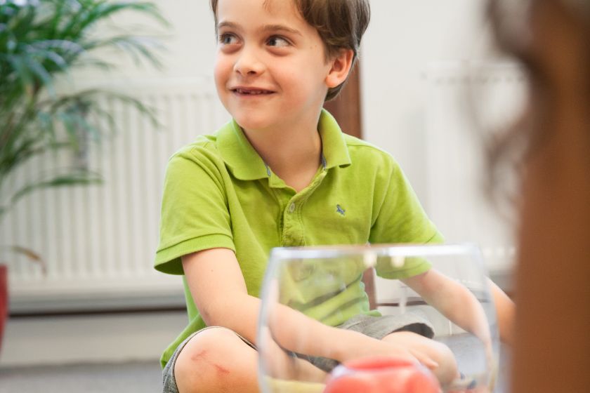 Ein kleiner Junge sitzt im Schneidersitz und lächelt.