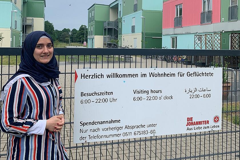 Eine Mitarbeiterin im Bundesfreiwilligendienst steht vor einer Flüchtlingsunterkunft