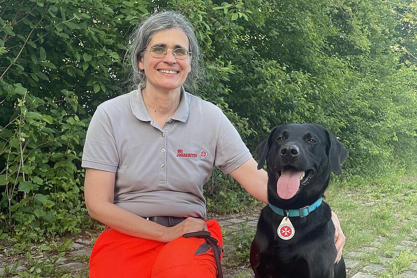 Eine Helferin der Rettungshundestaffel mit ihrem Hund im Wald