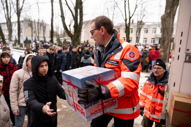 Johanniter verteilen Päckchen vom Johanniter-Weihnachtstrucker aus einem Lkw an Menschen
