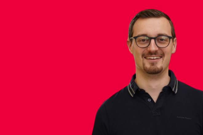 Portrait eines Mitarbeiters vor rotem Hintergrund