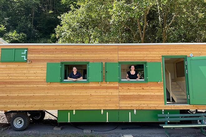 Zwei Johanniter-Mitarbeiter schauen aus dem Fenster des Bauwagens der Waldkita in Rech
