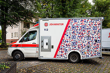 Ein beklebter Rettungswagen mit QR-Code-Design.