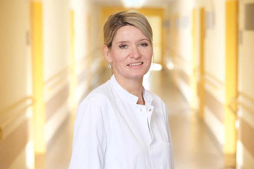 Blonde Frau in Arztkittel im Krankenhausflur 