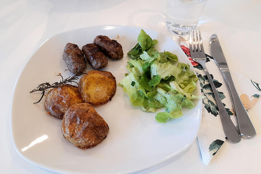 Fertiges Gericht mit Salat und Cevapcici, leckere auf einem Teller angerichtet.