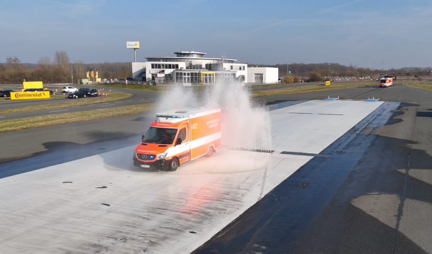 Ein Rettungswagen fährt durch Wasserfontänen