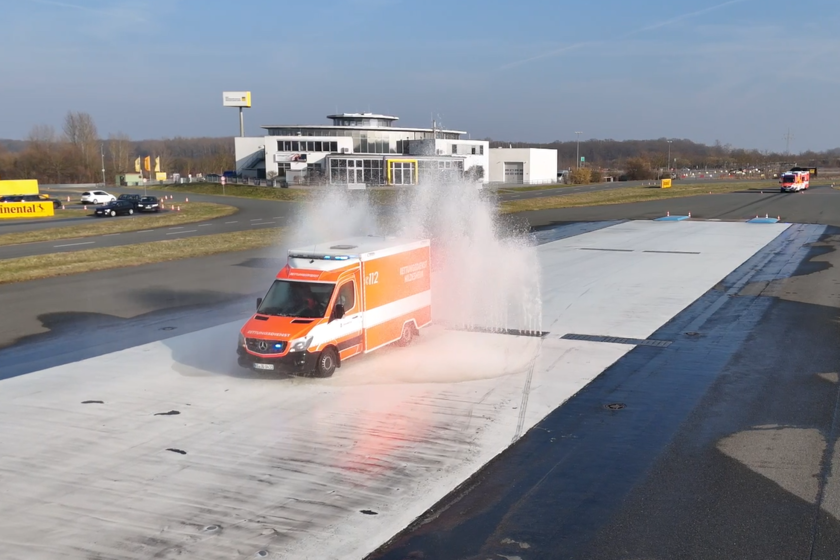 Ein Rettungswagen fährt durch Wasserfontänen