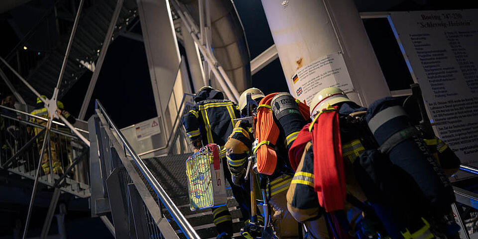 Ehrenamtliche Feuerwehrleute der Feuerwehr Speyer laufen die Treppe zur Boeing 747 im Technik Museum Speyer hoch.
