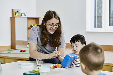 Eine Johanniter-Erzieherin bereitet einem Kita-Kind sein Essen zu.