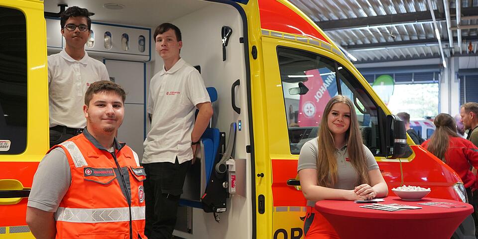 Zwei Menschen aus dem Katastrophenschutz vor einem Krankentransportwagen beim Tag der offenen Tür 2024