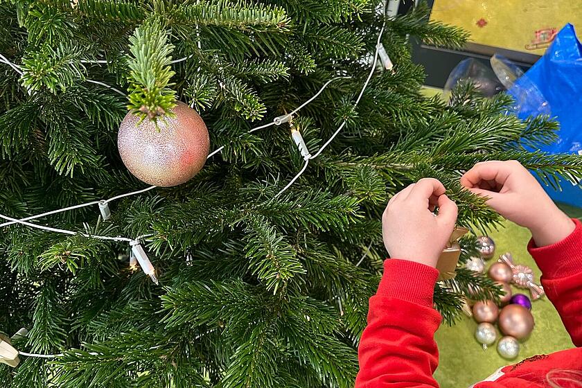 Ein Kind hängt einen Aufhänger an den Baum
