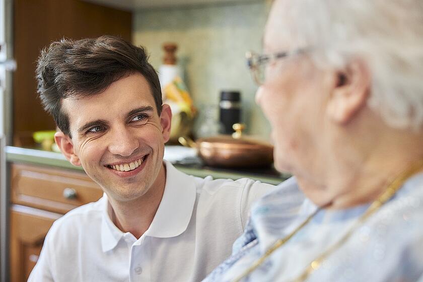 Ein Auszubildender in der Pflege betreut eine ältere Dame