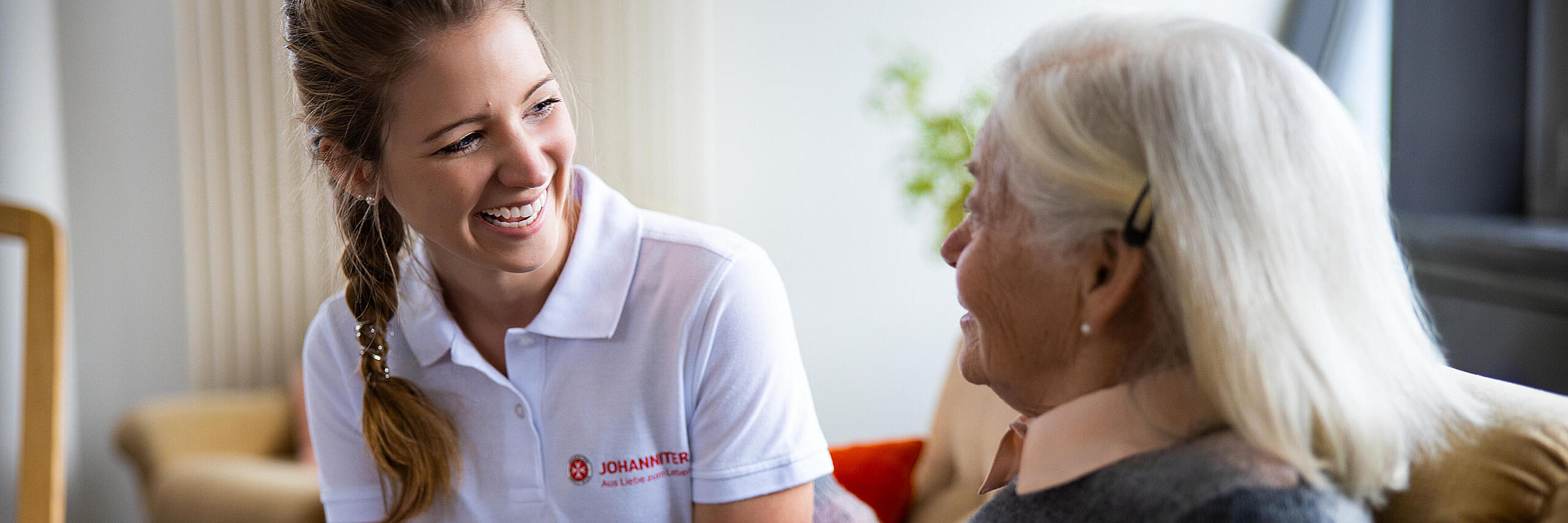 Eine Auszubildende in der Pflege unterhält sich mit einer älteren Frau