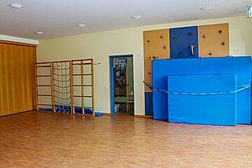 Turnraum einer Kita mit Kletterwand, Sprossenwand und großen blauen Matten.
