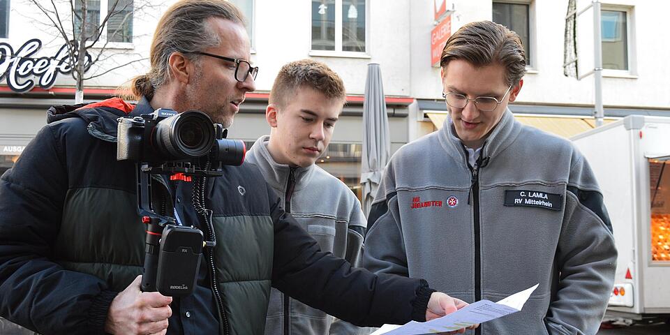 Ein Kameramann bespricht ein Drehskript mit zwei FSJlern