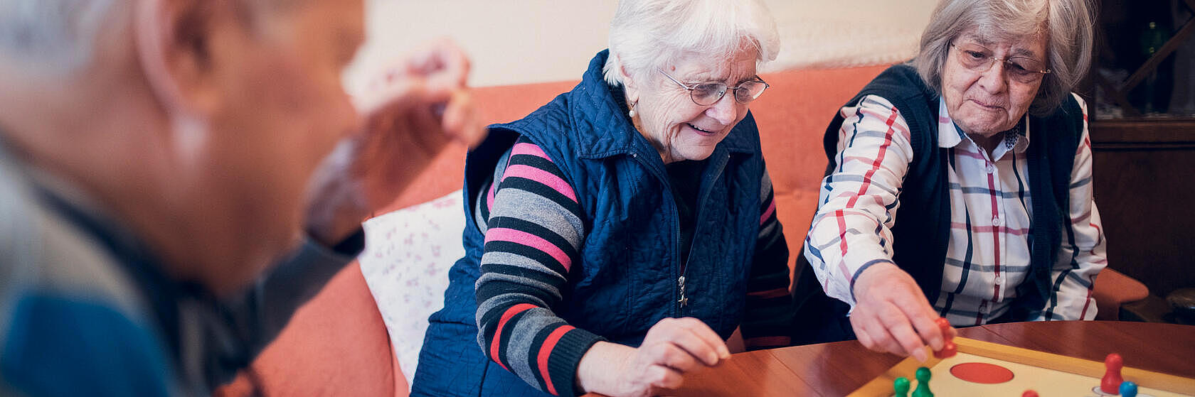 zwei Damen und ein Herr spielen Mensch-ärgere-dich-nicht