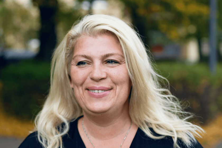 Kopfporträt einer blonden, lächelnden Frau mit offenen Haaren