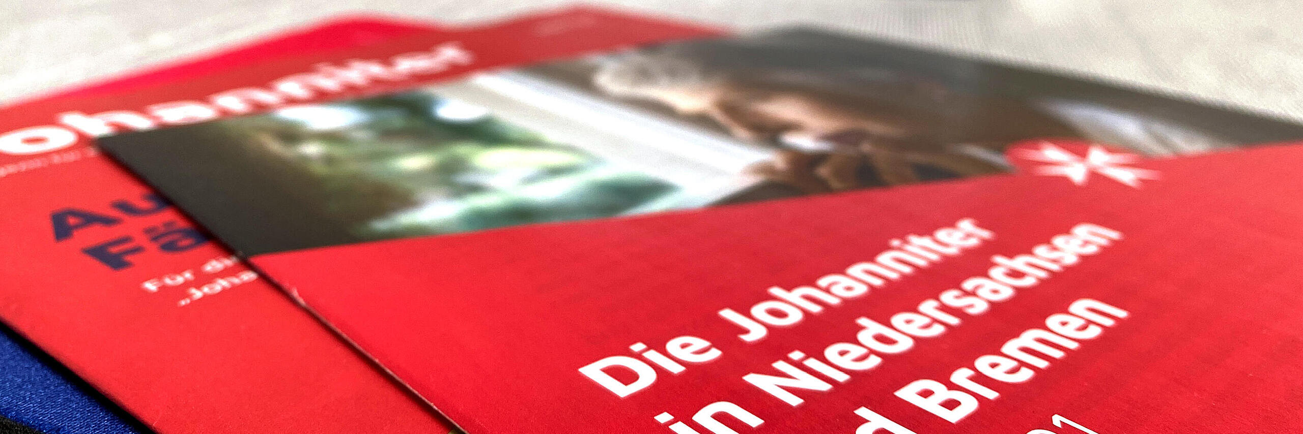 Publikationen (JO, Landesbeileger) der Johanniter liegen aufeinander auf einem Tisch
