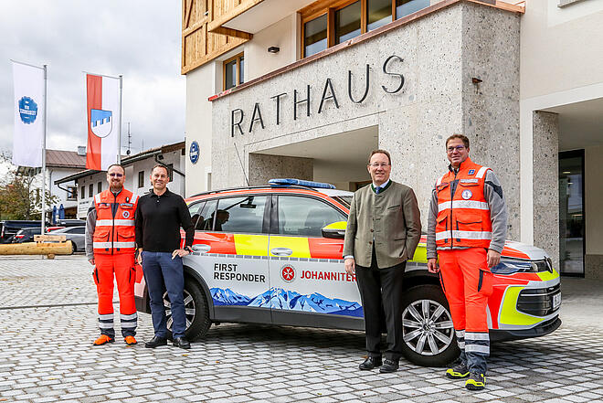 Zwei Bürgermeister und zwei Einsatzkräfte stehen vor neuem Einsatzfahrzeug. Im Hintergrund das Rathausgebäude.