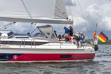 Crew auf dem Segelboot der Johanniter setzt die Segel.