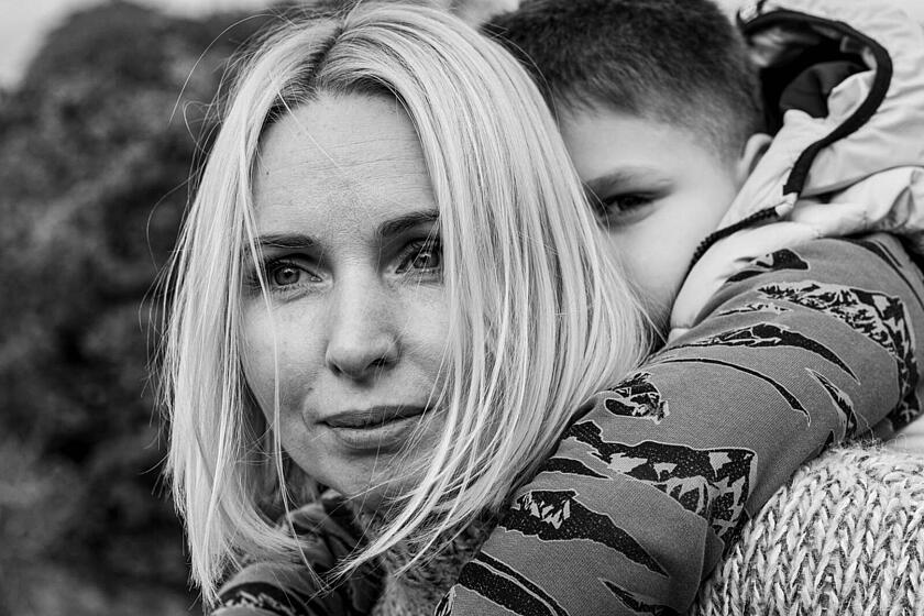 Eine schwarz-weiße Nahaufnahme einer Frau, die einen kleinen Jungen auf dem Rücken trägt.