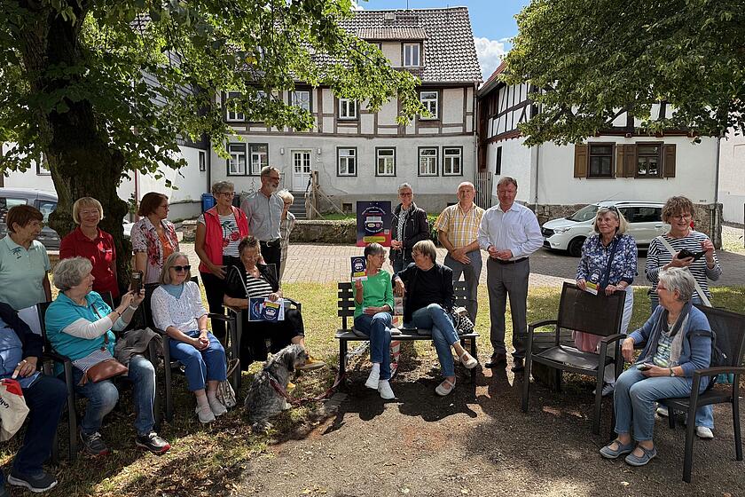 Viele Manschen als Gruppenfoto um Plaudertbank herum