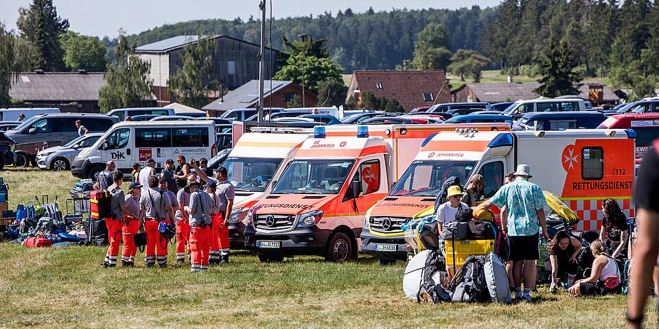 Mehrere Rettungswagen der Johanniter mit Einsatzkräften und Ausrüstung auf dem Festivalparkplatz