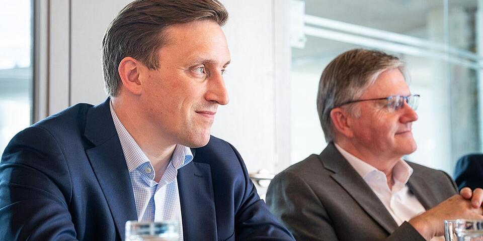 Zwei Männer im Anzug an einem Tisch im Gespräch