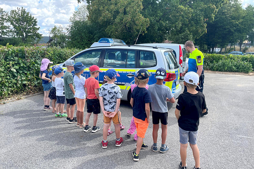 Ein Polizist erklärt Vorschulkindern die Besonderheiten eines Polizeiwagens