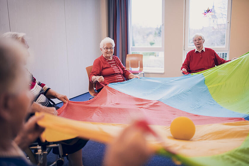 Seniorengruppe bei sportlichen Aktivitäten mit Ball und Tuch