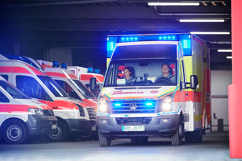 Ein Johanniter-Rettungswagen fährt mit Blaulicht aus der Fahrzeughalle.