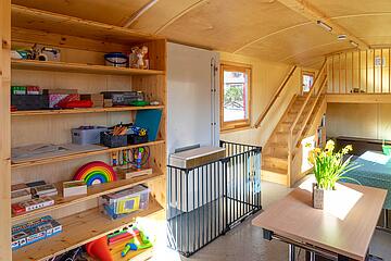 Im Bauwagen des Naturkindergartens Oststeinbek der Johanniter: Ein Schrank mit Spielsachen und Tische zum Sitzen.