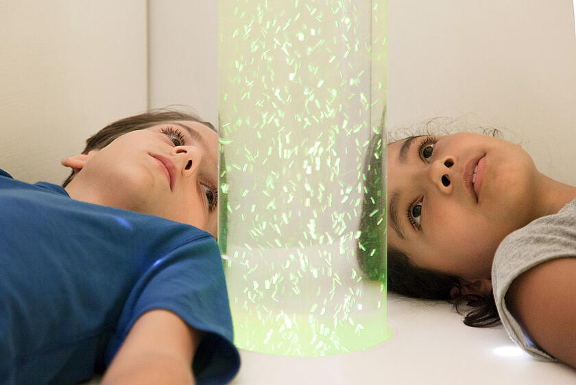 Zwei Kinder einer Lacrima Gruppe schauen sich eine Wasserblasensäule an.