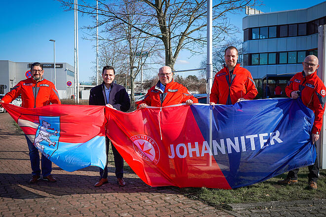 Von links: Michele Sciacca, Bürgermeister Claudio Provenanzo. Ortsbeauftragter Thomas Silbermann, Philipp Petzold (Teamleiter Rettungsdienst) und Michael Merz (Fachbereichsleiter Rettungsdienst) beim Hissen der Flaggen vor der Johanniter-Rettungswache Garbsen.