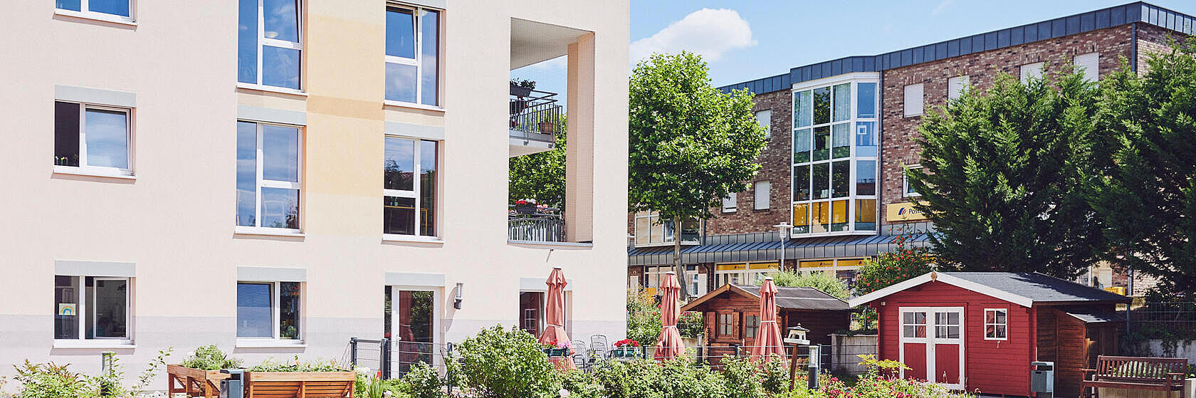 Blick auf die Fassade mit Sitzgelegenheiten und schönen Grünflächen davor