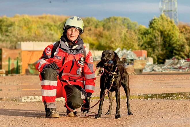 Jutta Sprenger und ihre Labradorhündin Eliza vor einem Trümmerhintergrund.