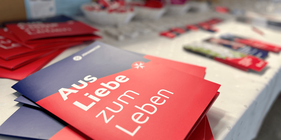 mehrere Broschüren, außen rot und blau, liegen auf einem Tisch aus