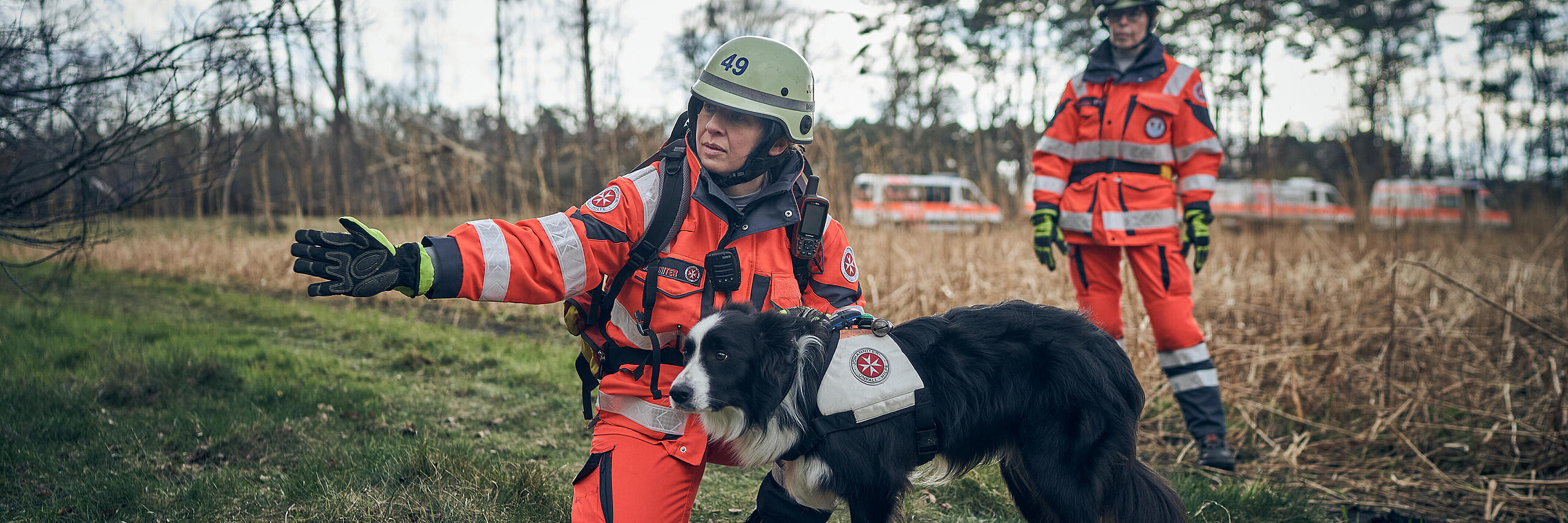 Zwei Einsatzkräfte der Rettungshundestaffel mit einem Rettungshund im Wald