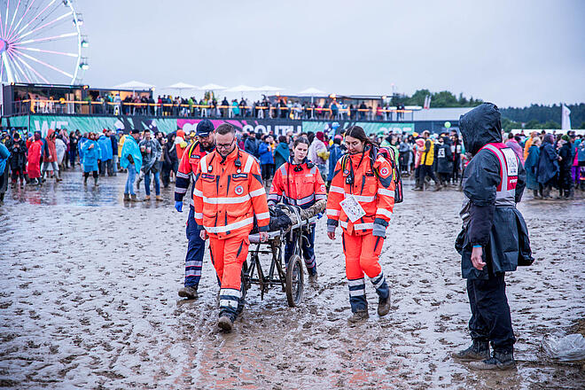 Helfer bringen verletzten Festivalbesucher mit einer Trage in Sicherheit