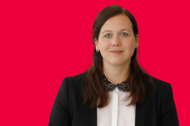 Portrait einer Mitarbeiterin vor rotem Hintergrund