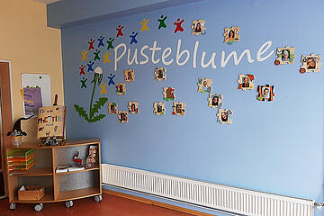 An einer Wand sind die Bilder der Teammitglieder des Johanniter-Haus Pusteblume angebracht.