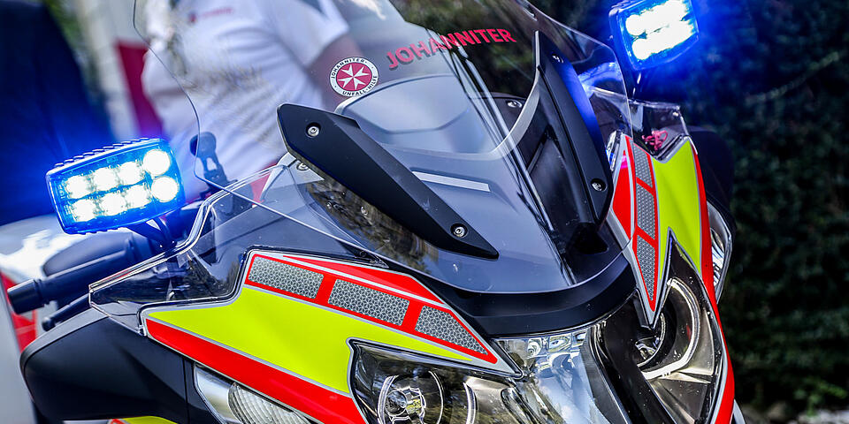 Detailaufnahme einer Motorradfront mit blinkenden Blaulichtern und Johanniter-Aufschrift.
