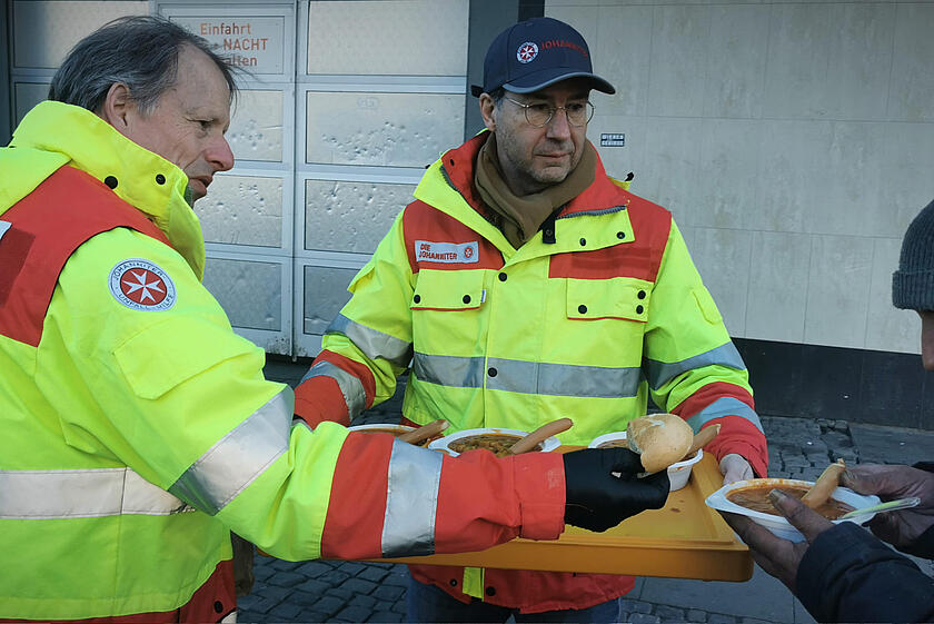 Ehrenamtliche Johanniter verteilen Essen an Bedürftige.