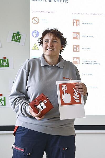 Eine Lehrkraft der Brandschutz-Ausbildung steht vor einer Leinwand
