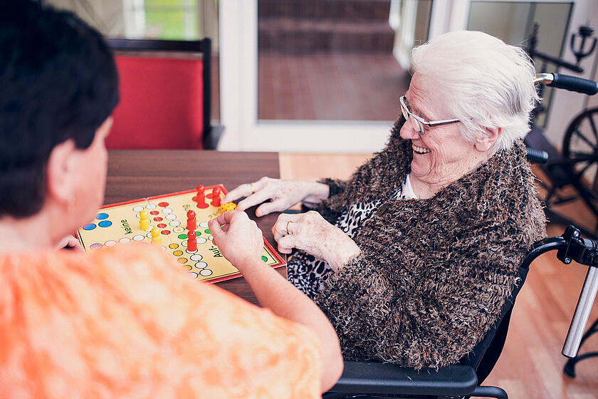 Bewohnerin und Pflegekraft spielen "Mensch ärgere dich nicht" im Johanniter-Haus Mutter Eva von Tiele-Winckler