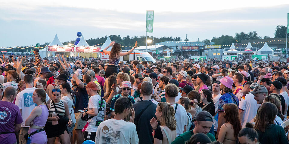 Große Menschenmenge auf dem Festivalgelände vor Bühnen und Versorgungszelten.