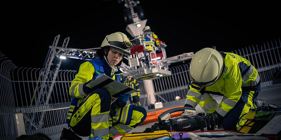 Eine Sanitäterin schreibt die Vitalwerte eines Patienten unterhalb der Boeing 747 im Technik Museum Speyer auf. Im Hintergrund ist die Drehleiter der Feuerwehr zu sehen.