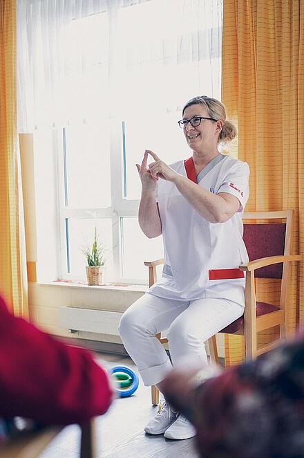 Eine Mitarbeiterin führt eine Übung zum Training der Feinmotorik vor
