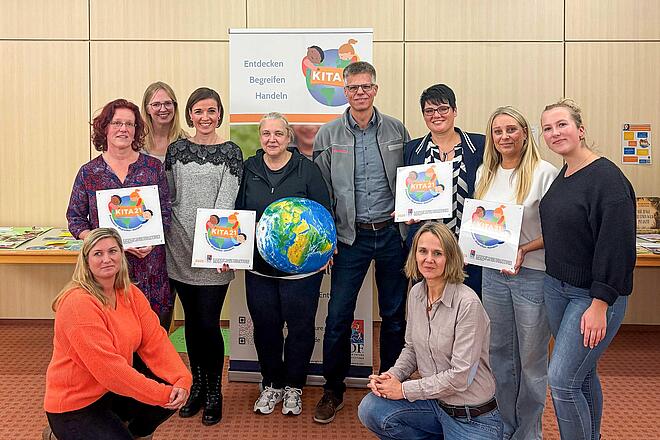 Gruppenfoto mit zehn Personen, die vier Plaketten der Auszeichnung KITA21 hochhalten.